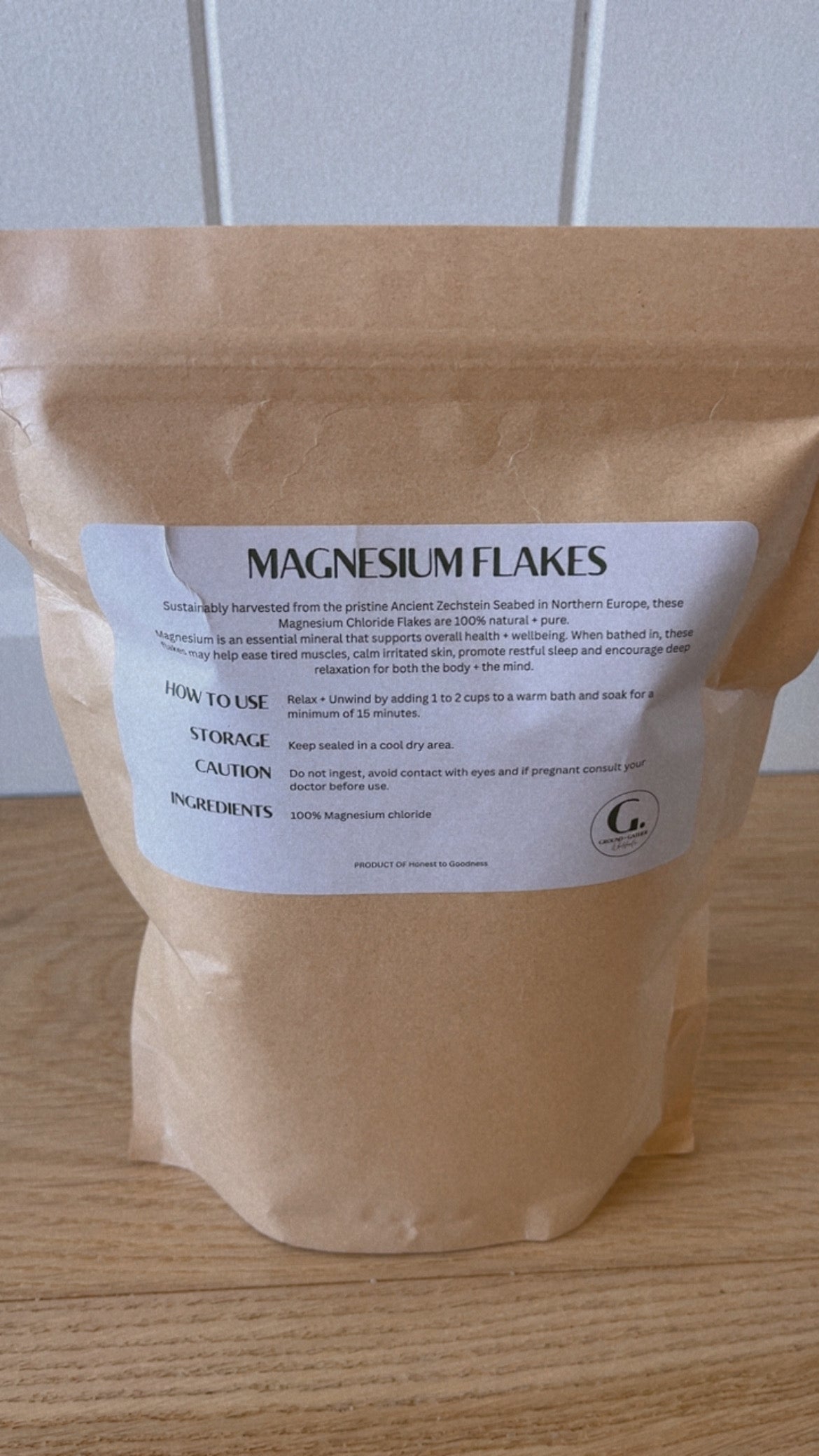 Kraft paper bag of magnesium flakes with a label on a wooden surface.