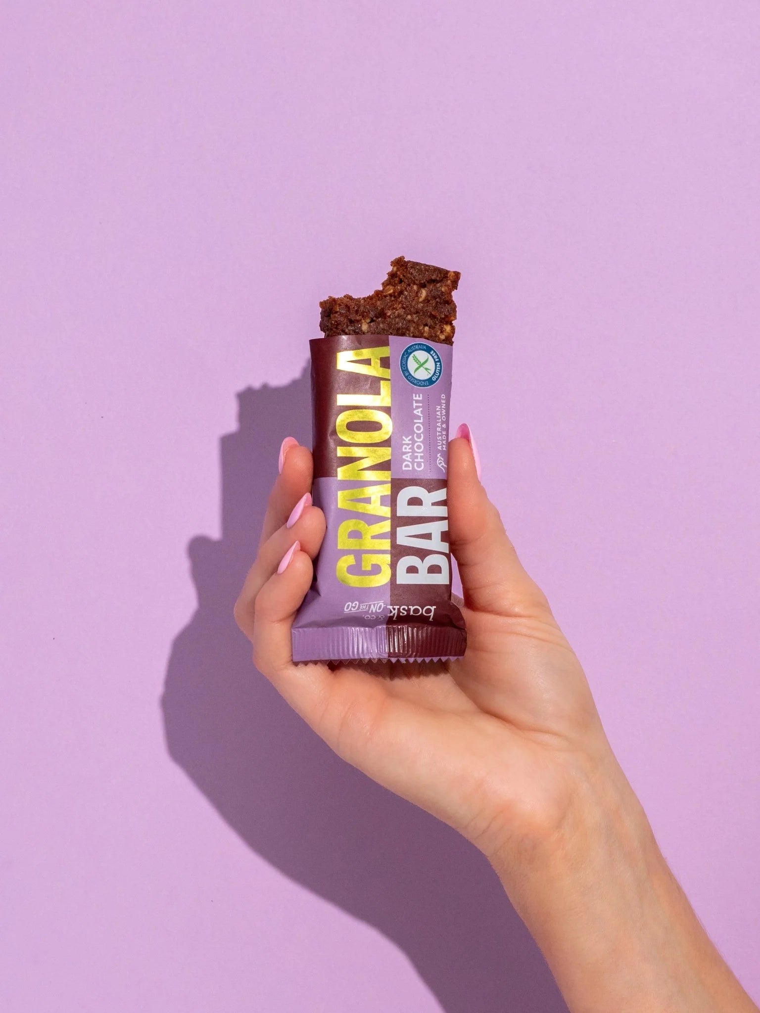 Hand holding a granola bar against a purple background